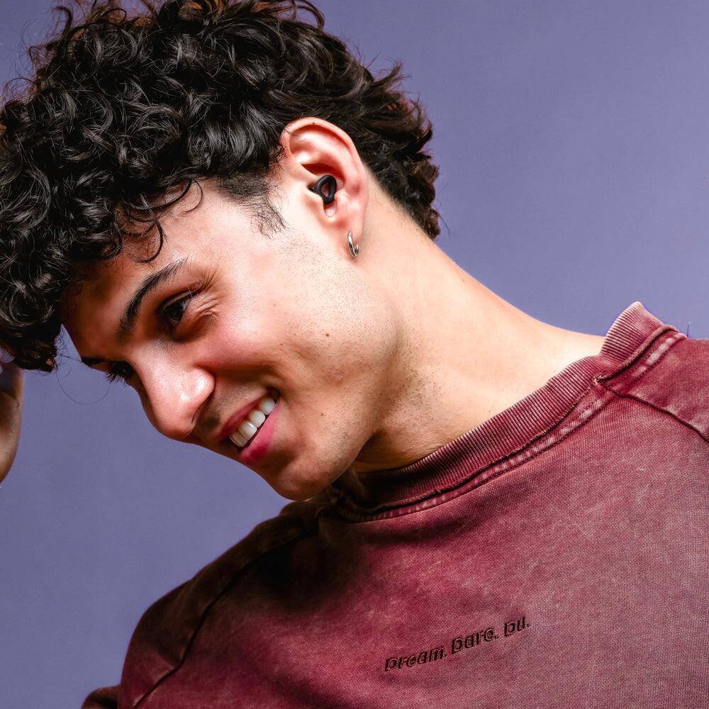 Young man wearing ZENZ Unwind Earplugs in Onyx Black for noise reduction earplugs and enhanced comfort.