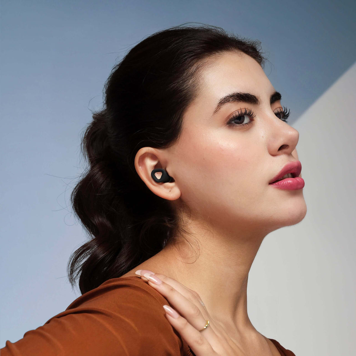 ZENZ Unwind Pro Earplugs in Onyx Black for noise reducing earplugs for better sleep, worn by a woman.