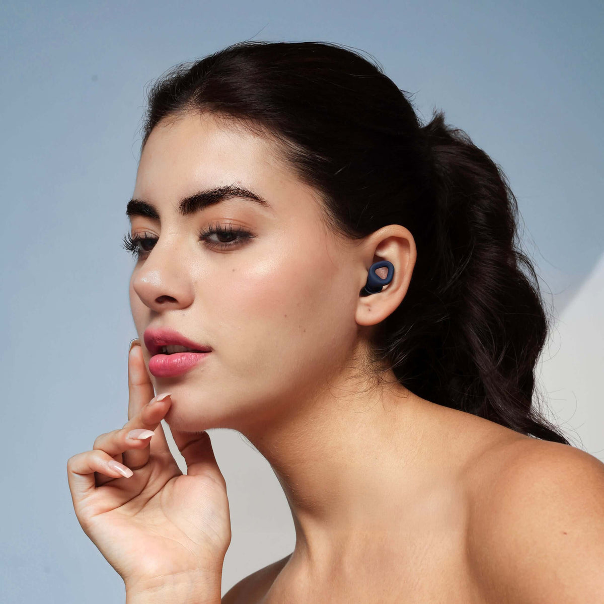 Model wearing ZENZ Unwind Pro Earplugs in Lagoon Navy, showcasing noise reducing earplugs for better sleep.