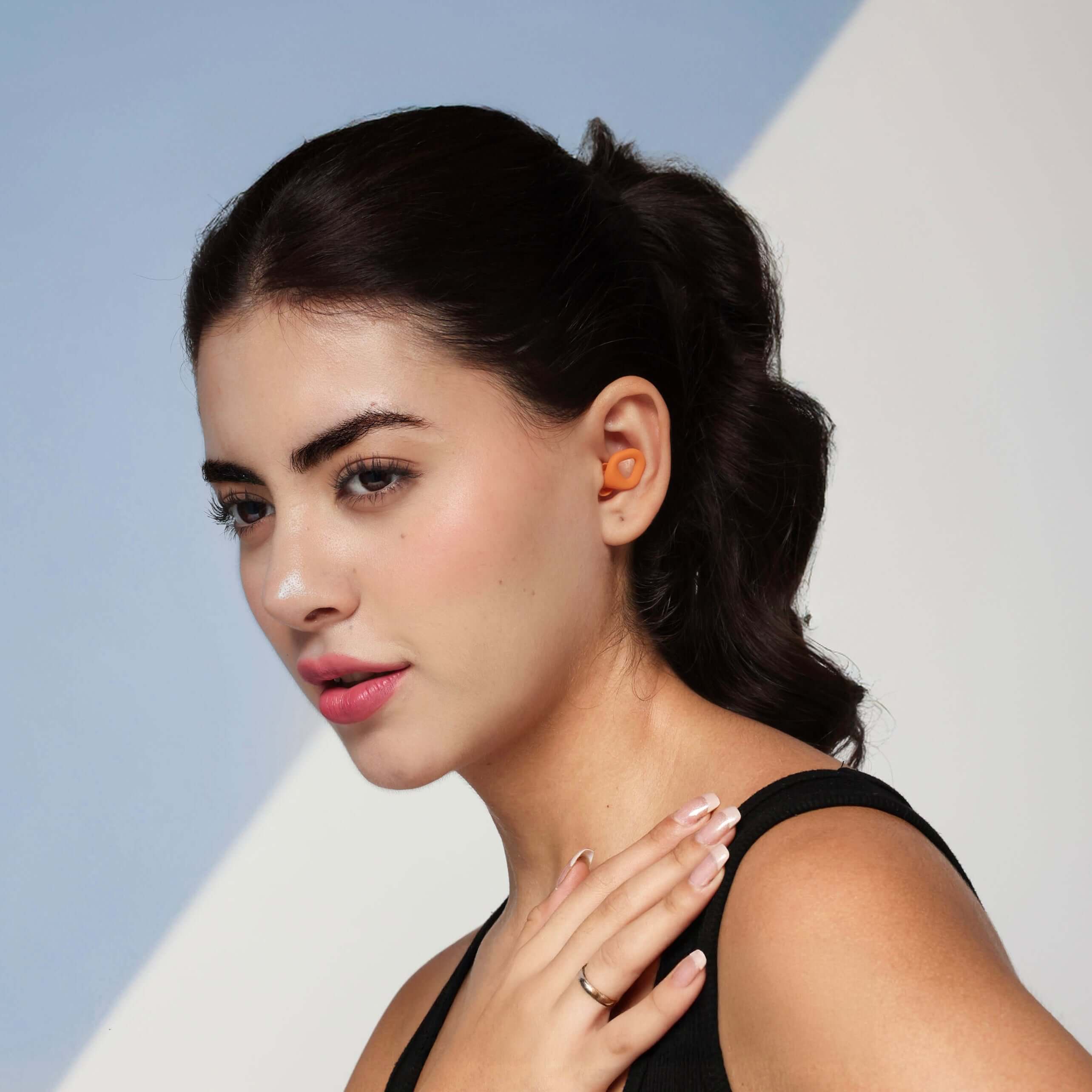 Model wearing ZENZ Unwind Pro noise reducing earplugs in blaze orange for enhanced comfort and noise reduction.
