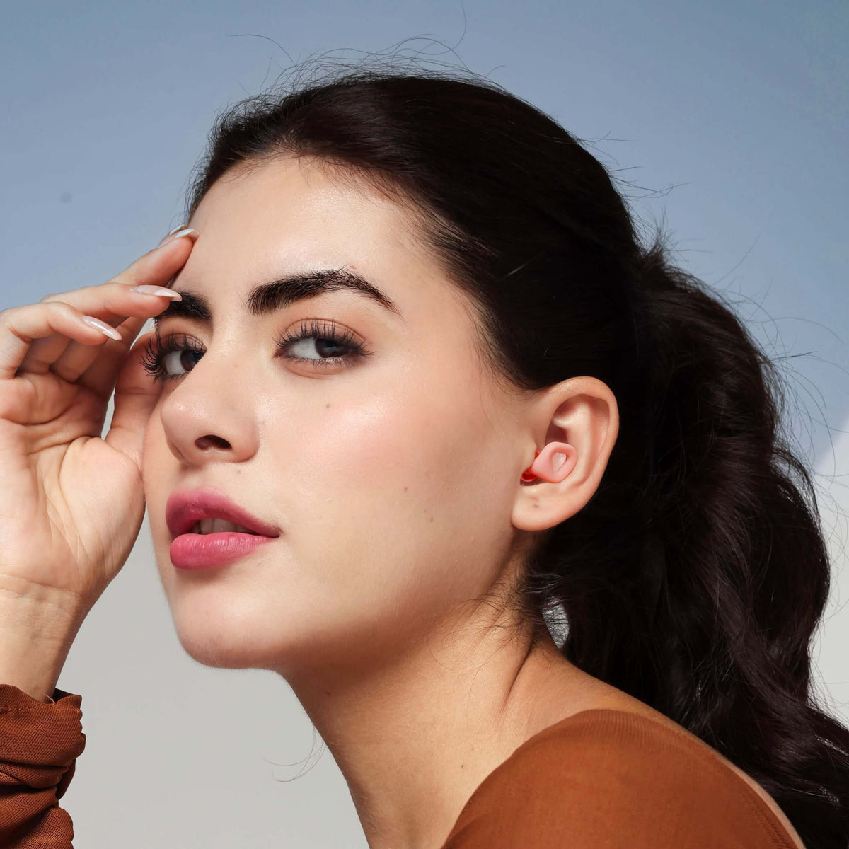 Beauty shot of a woman wearing ZENZ noise reduction earplugs for sleep in Mystic Pink.